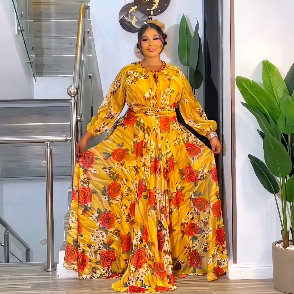 A woman modeling a long-sleeved yellow maxi dress with a red and orange floral print, standing in an indoor setting.